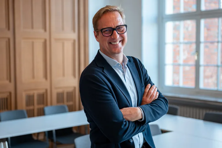 Volker Meise mit verschränkten Armen in einem Seminarraum